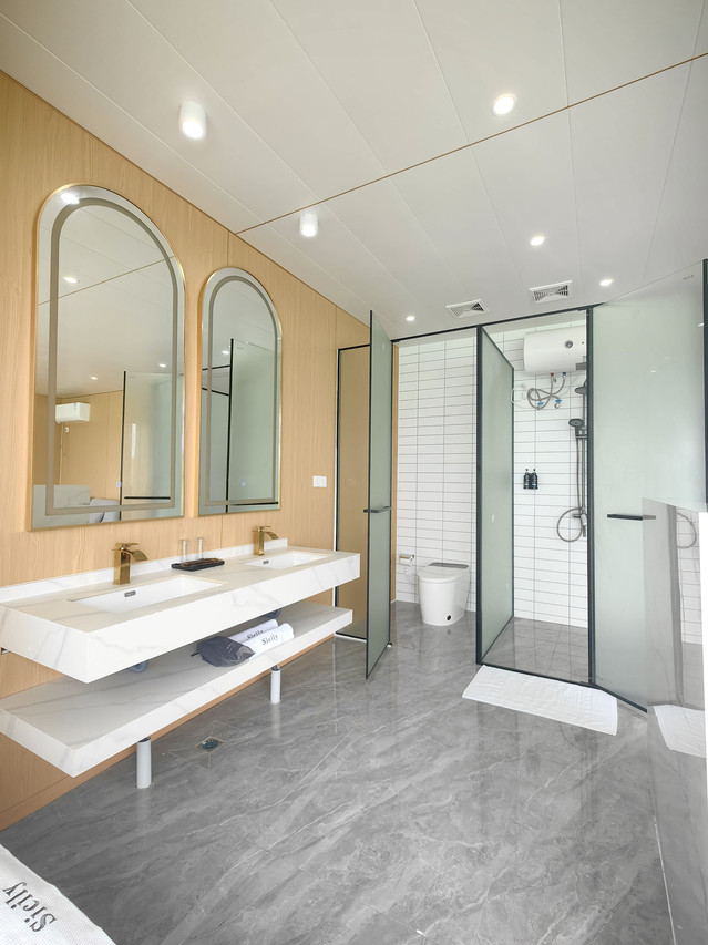 Bright modern bathroom with floating dual vanity and arched mirrors at Sicily Hotel