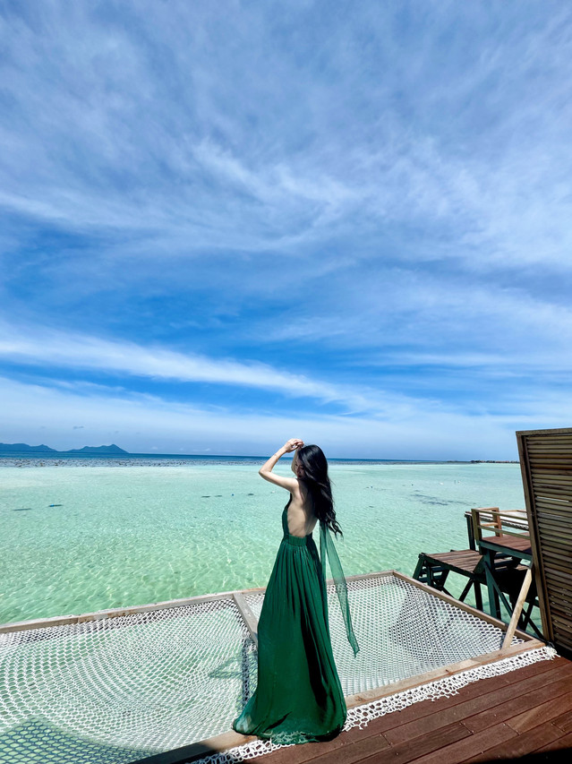 Guest enjoying the ocean breeze on a private overwater mesh bed at Sicily Hotel