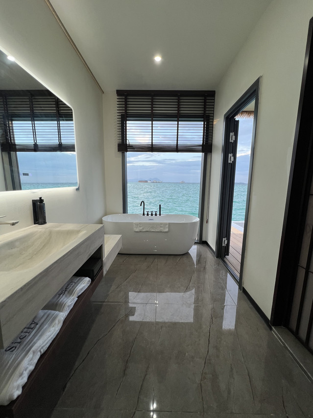 Moody modern bathroom featuring dark marble tiles and white soaking tub at Sicily Hotel